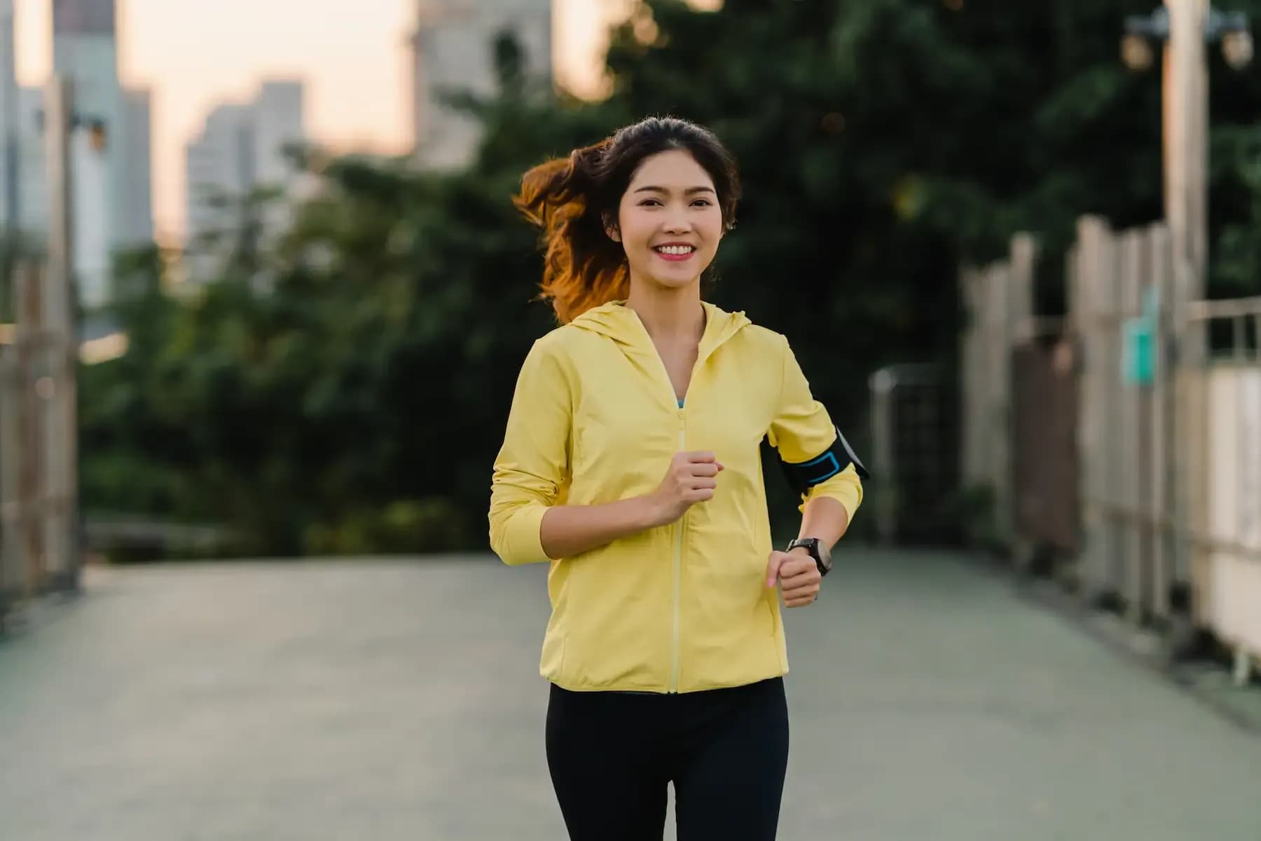 A woman in a bright yellow jacket happily going for a morning jog